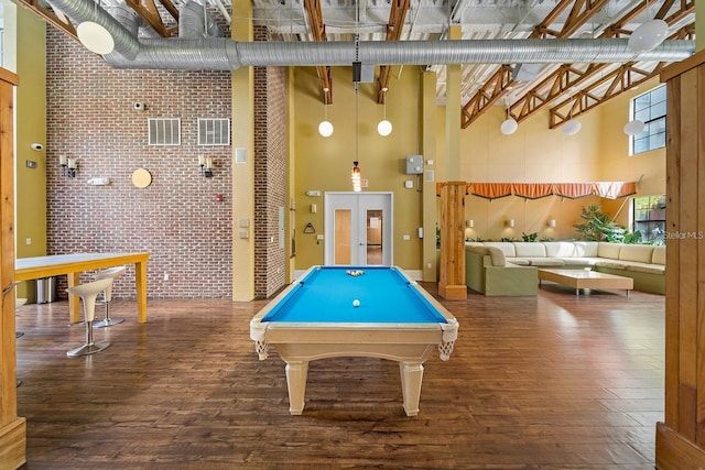 rec room featuring a high ceiling, brick wall, dark wood-type flooring, and pool table