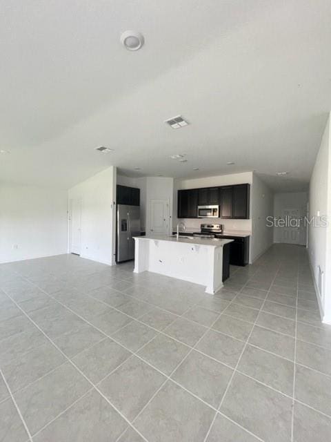 kitchen featuring light tile patterned flooring, stainless steel appliances, and a center island with sink