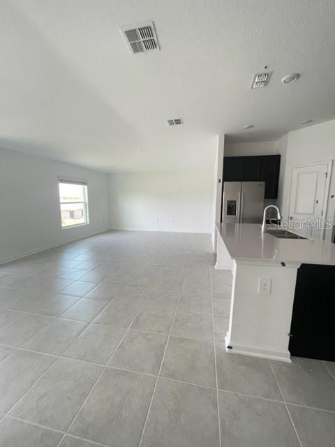 1148 Pomelo St, Davenport, FL 33837 - kitchen featuring sink, light tile patterned floors, and stainless steel fridge