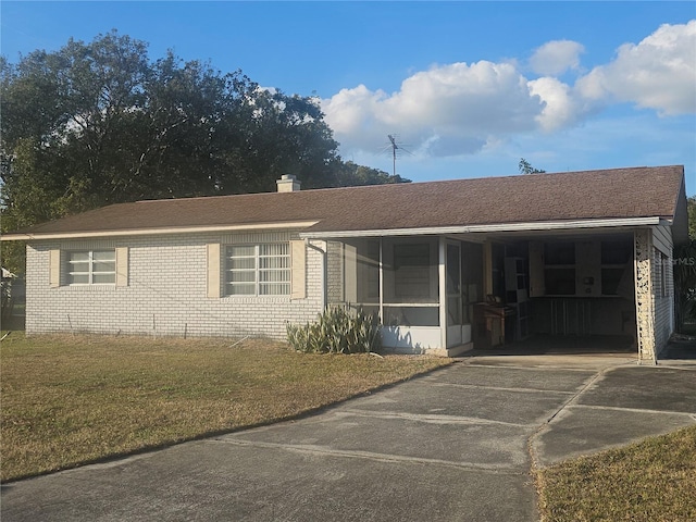 ranch-style house with a carport, a sunroom, and a front lawn