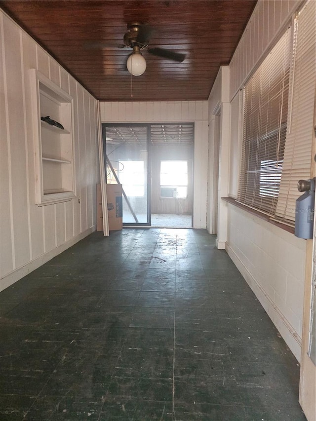 empty room with wood ceiling, ceiling fan, and built in shelves