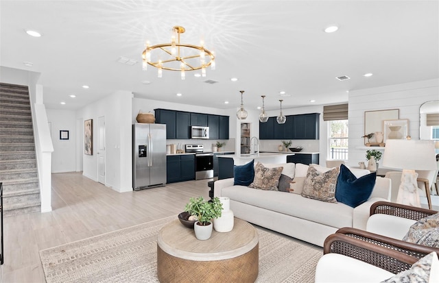 living room with light hardwood / wood-style floors, sink, and a notable chandelier