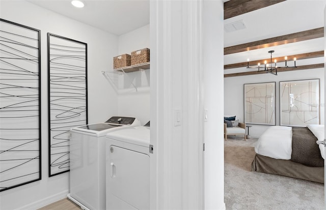 laundry room with light carpet, washing machine and clothes dryer, and an inviting chandelier