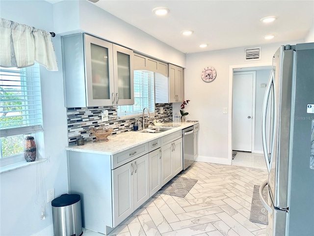 kitchen with appliances with stainless steel finishes, sink, gray cabinetry, and backsplash