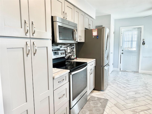 kitchen with stainless steel appliances, tasteful backsplash, and light stone countertops