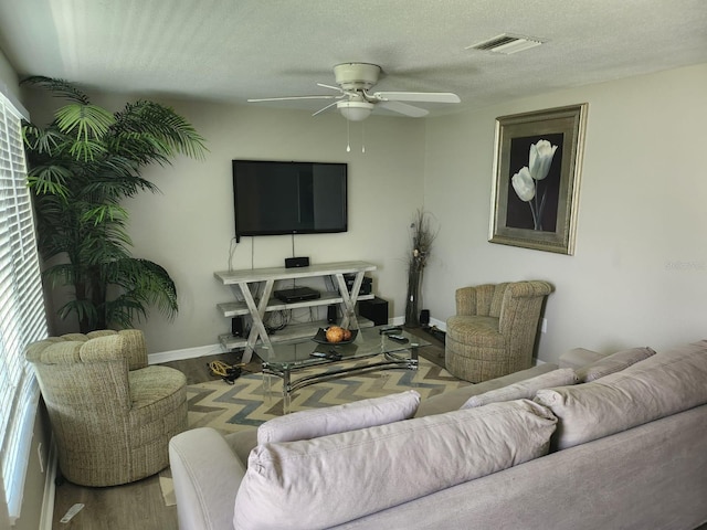 living room featuring ceiling fan, hardwood / wood-style flooring, and a textured ceiling