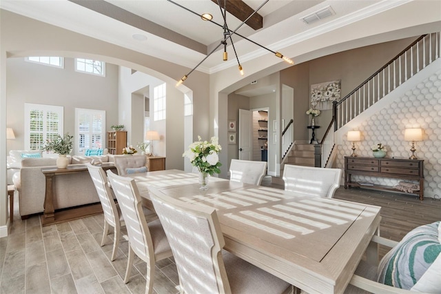 dining space with hardwood / wood-style flooring, crown molding, and a high ceiling