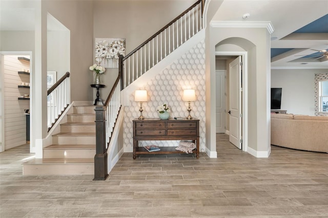 stairway featuring wood-type flooring, ornamental molding, and ceiling fan