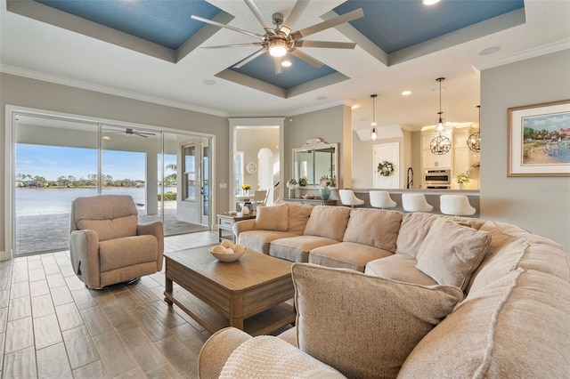 living room with a water view, coffered ceiling, hardwood / wood-style floors, and crown molding