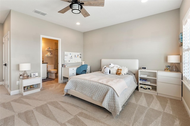 bedroom with ensuite bath, light colored carpet, and ceiling fan