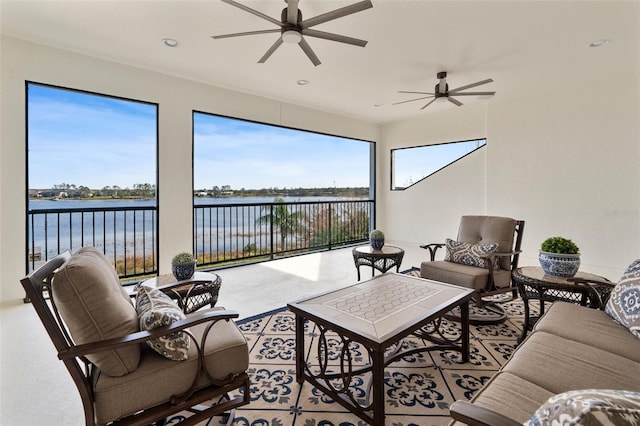 sunroom with ceiling fan and a water view