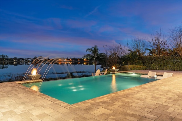 pool at dusk featuring a patio area, pool water feature, and a water view