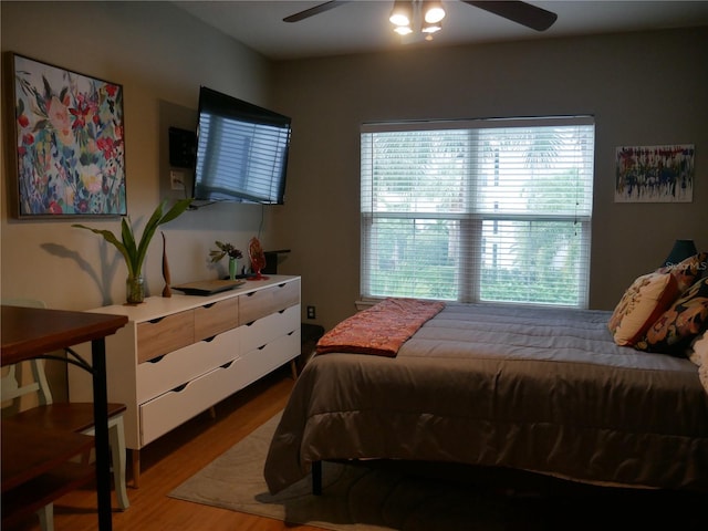 bedroom with ceiling fan, hardwood / wood-style floors, and multiple windows