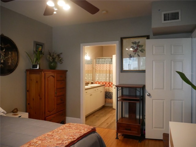 bedroom featuring ceiling fan, ensuite bath, sink, and light hardwood / wood-style floors