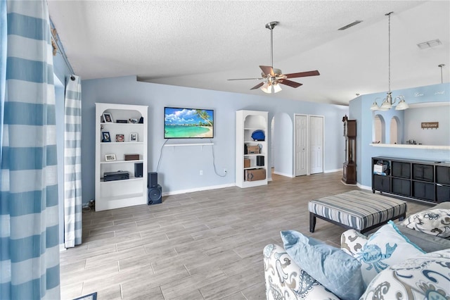 living room featuring lofted ceiling, ceiling fan, and a textured ceiling