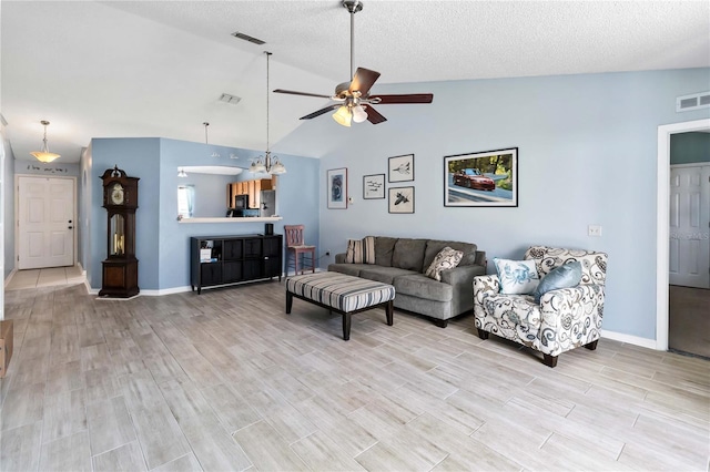 living room featuring ceiling fan, vaulted ceiling, light hardwood / wood-style flooring, and a textured ceiling