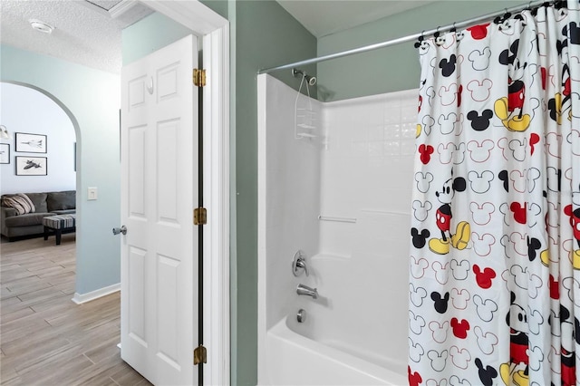 bathroom with hardwood / wood-style floors, shower / tub combo, and a textured ceiling