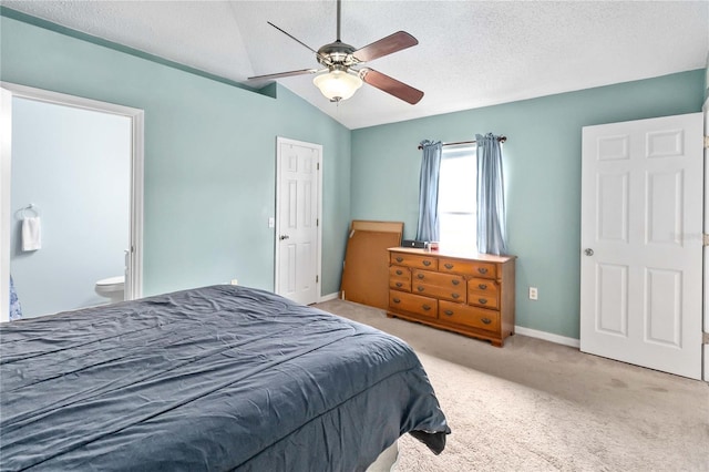 carpeted bedroom with ceiling fan, ensuite bathroom, vaulted ceiling, and a textured ceiling