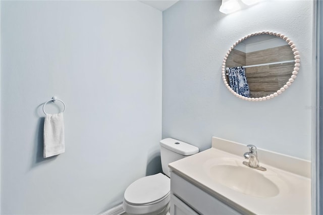 bathroom with walk in shower, vanity, and toilet