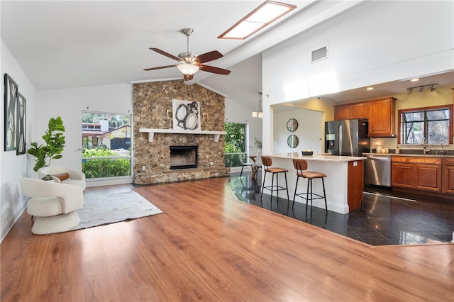 kitchen with a stone fireplace, dark hardwood / wood-style floors, sink, a breakfast bar area, and stainless steel appliances