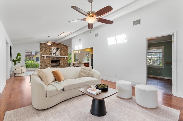 living room featuring ceiling fan, a healthy amount of sunlight, wood-type flooring, and a fireplace