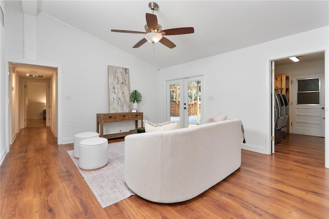 living room featuring vaulted ceiling, wood-type flooring, washing machine and clothes dryer, and french doors