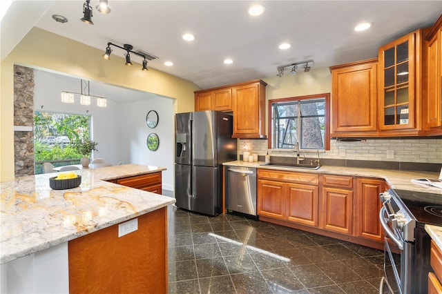 kitchen with sink, decorative backsplash, hanging light fixtures, stainless steel appliances, and light stone countertops