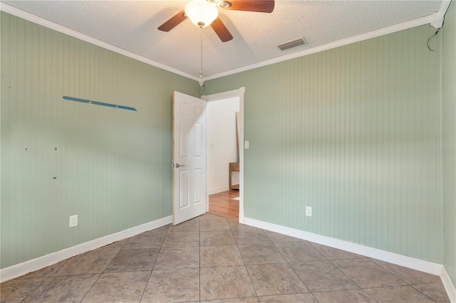 spare room with tile patterned flooring, crown molding, a textured ceiling, and ceiling fan