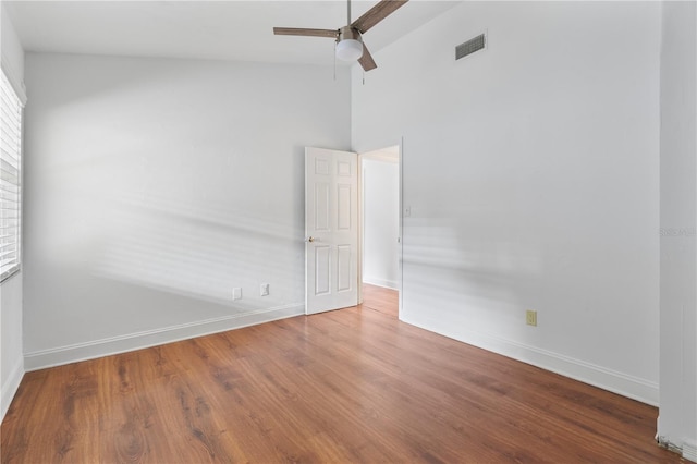 empty room featuring wood-type flooring, ceiling fan, and a high ceiling