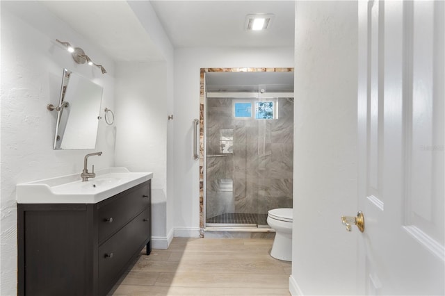 bathroom featuring hardwood / wood-style flooring, vanity, toilet, and a shower with door