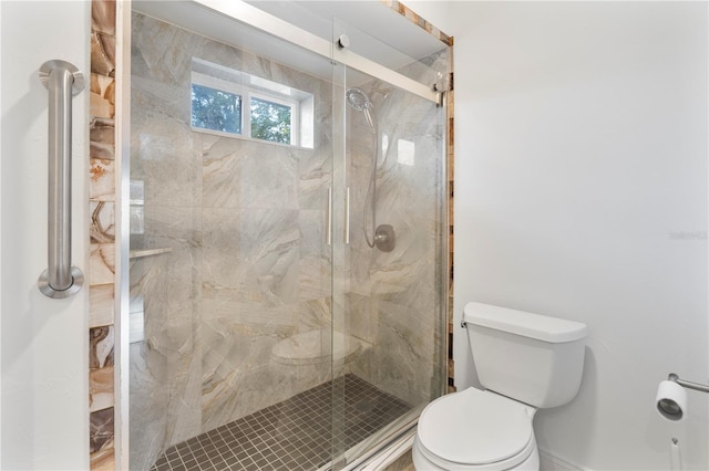 bathroom featuring toilet and a shower with shower door