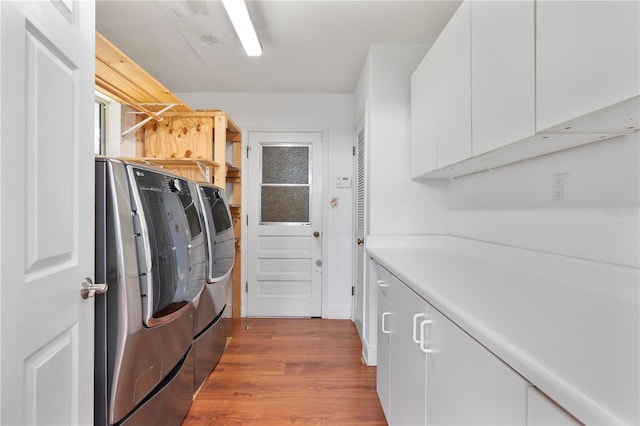 laundry area with cabinets, washer and clothes dryer, and light hardwood / wood-style floors