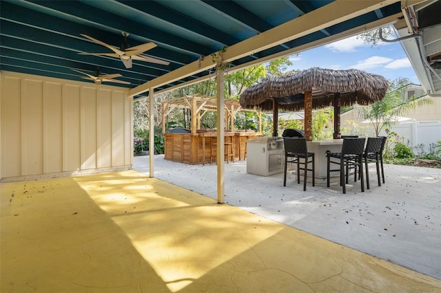 view of patio featuring a pergola, an outdoor bar, ceiling fan, and exterior kitchen