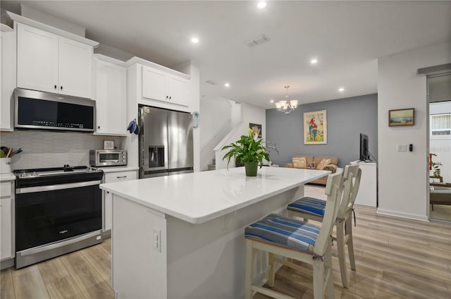 kitchen featuring appliances with stainless steel finishes, a kitchen breakfast bar, a kitchen island, and white cabinets