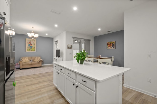 kitchen with pendant lighting, a center island, white cabinets, and light wood-type flooring