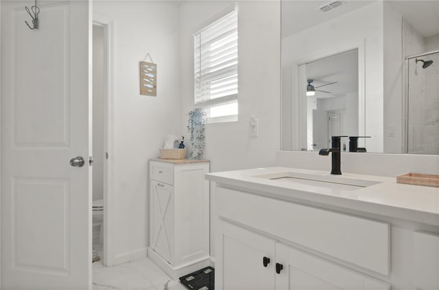 bathroom with ceiling fan, vanity, toilet, and a shower with shower door