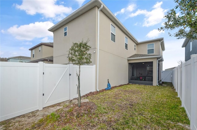 back of property with a lawn and a sunroom