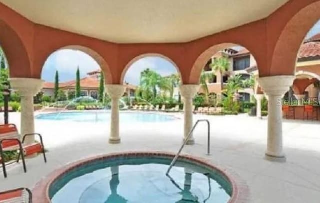 view of swimming pool with a community hot tub and a patio area