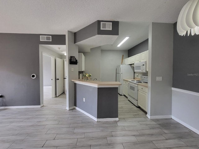 kitchen featuring a peninsula, white appliances, light countertops, and visible vents