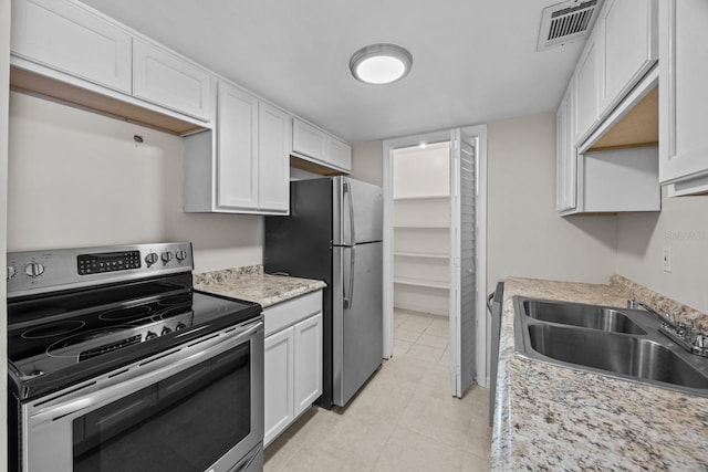 kitchen featuring sink, appliances with stainless steel finishes, light stone counters, white cabinets, and light tile patterned flooring