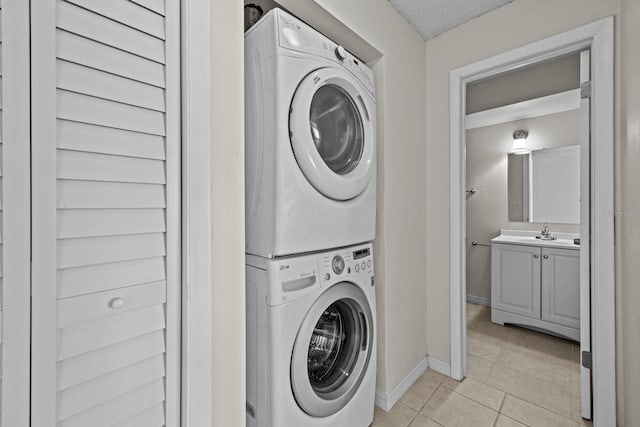 laundry room with light tile patterned flooring, stacked washer / drying machine, and sink