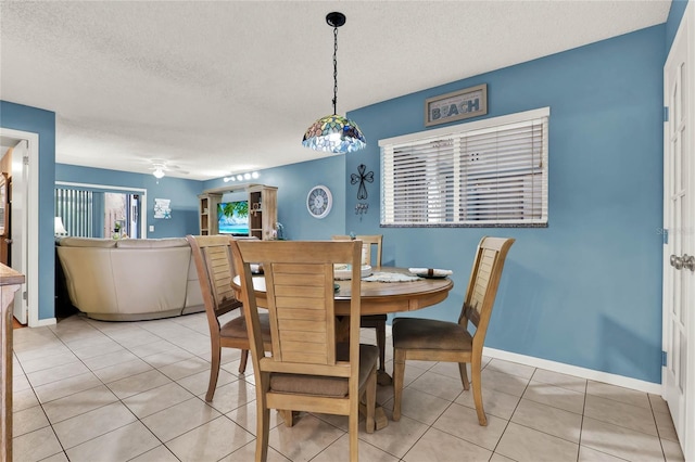 dining space with ceiling fan, light tile patterned floors, and a textured ceiling