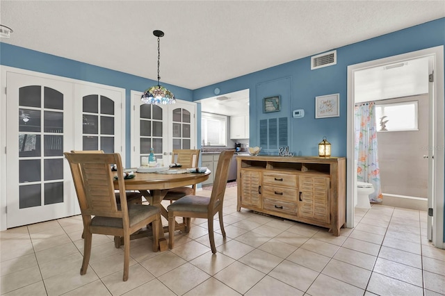 tiled dining space featuring sink, a wealth of natural light, a textured ceiling, and french doors