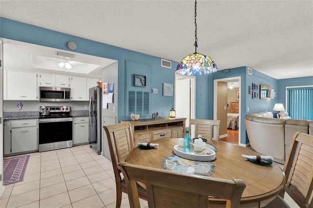 tiled dining room with a textured ceiling and ceiling fan