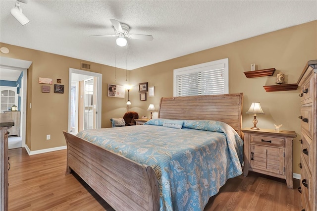 bedroom with ceiling fan, wood-type flooring, and a textured ceiling