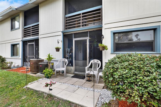 view of exterior entry with central AC unit and a patio