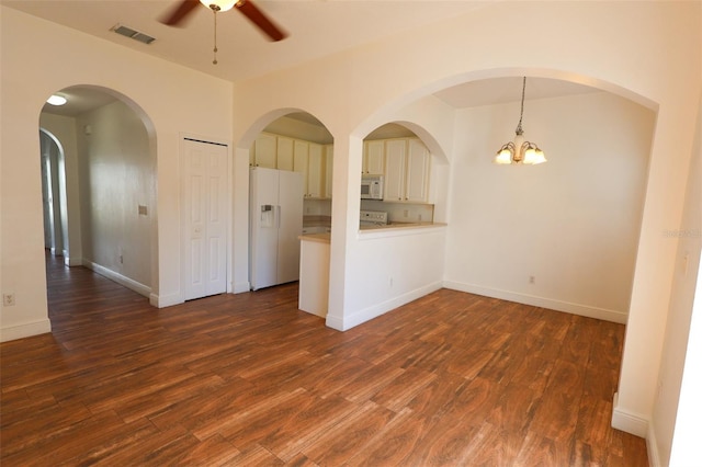 spare room featuring dark hardwood / wood-style floors and ceiling fan with notable chandelier