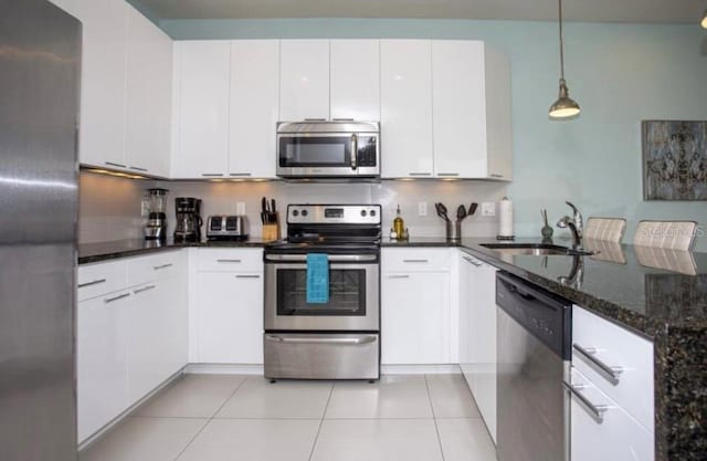 kitchen featuring white cabinetry, sink, stainless steel appliances, and dark stone countertops