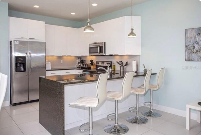 kitchen featuring hanging light fixtures, white cabinetry, appliances with stainless steel finishes, and tasteful backsplash