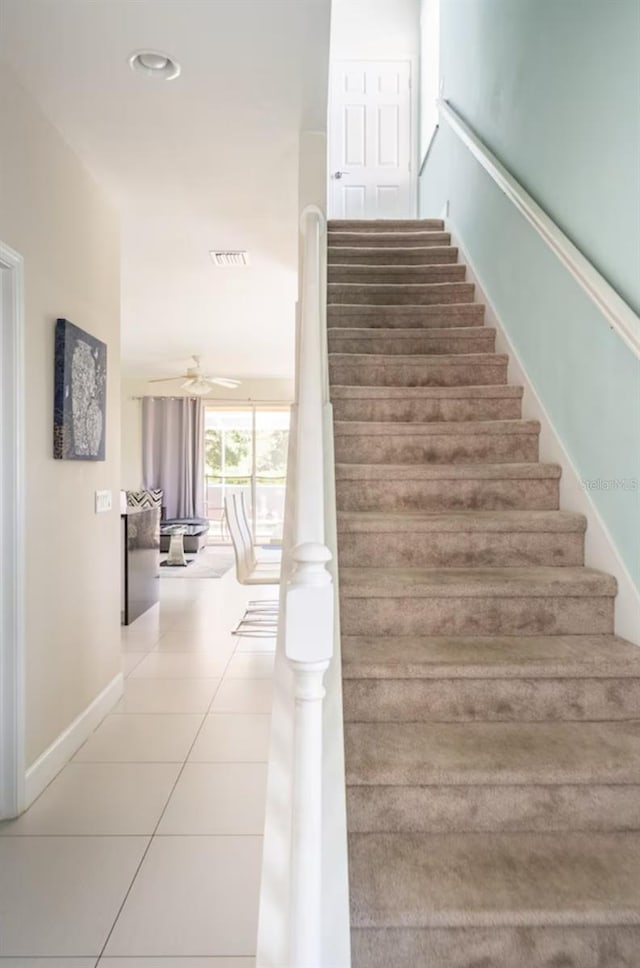 stairs featuring ceiling fan and tile patterned flooring